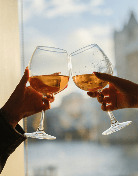 Two glasses of wine clinking with Tower Bridge in the background