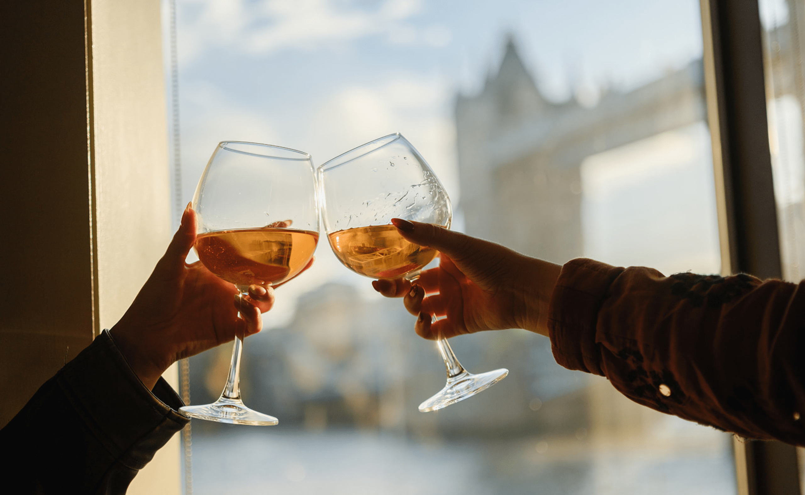 Two glasses of wine clinking with Tower Bridge in the background
