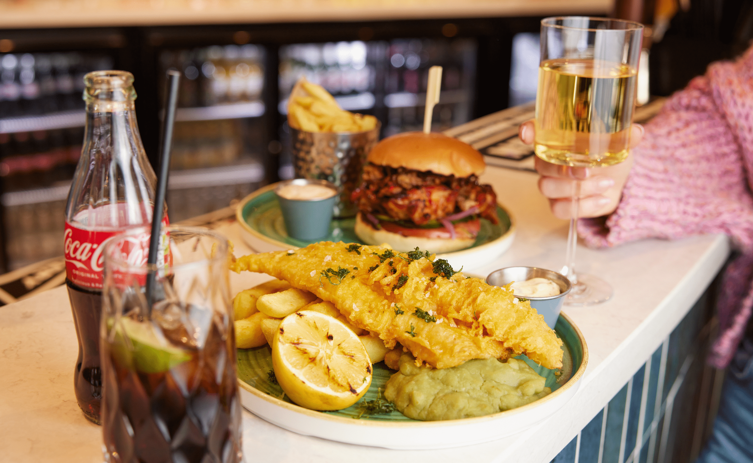 Photo of a plate of fish and chips with a glass of coke on the side