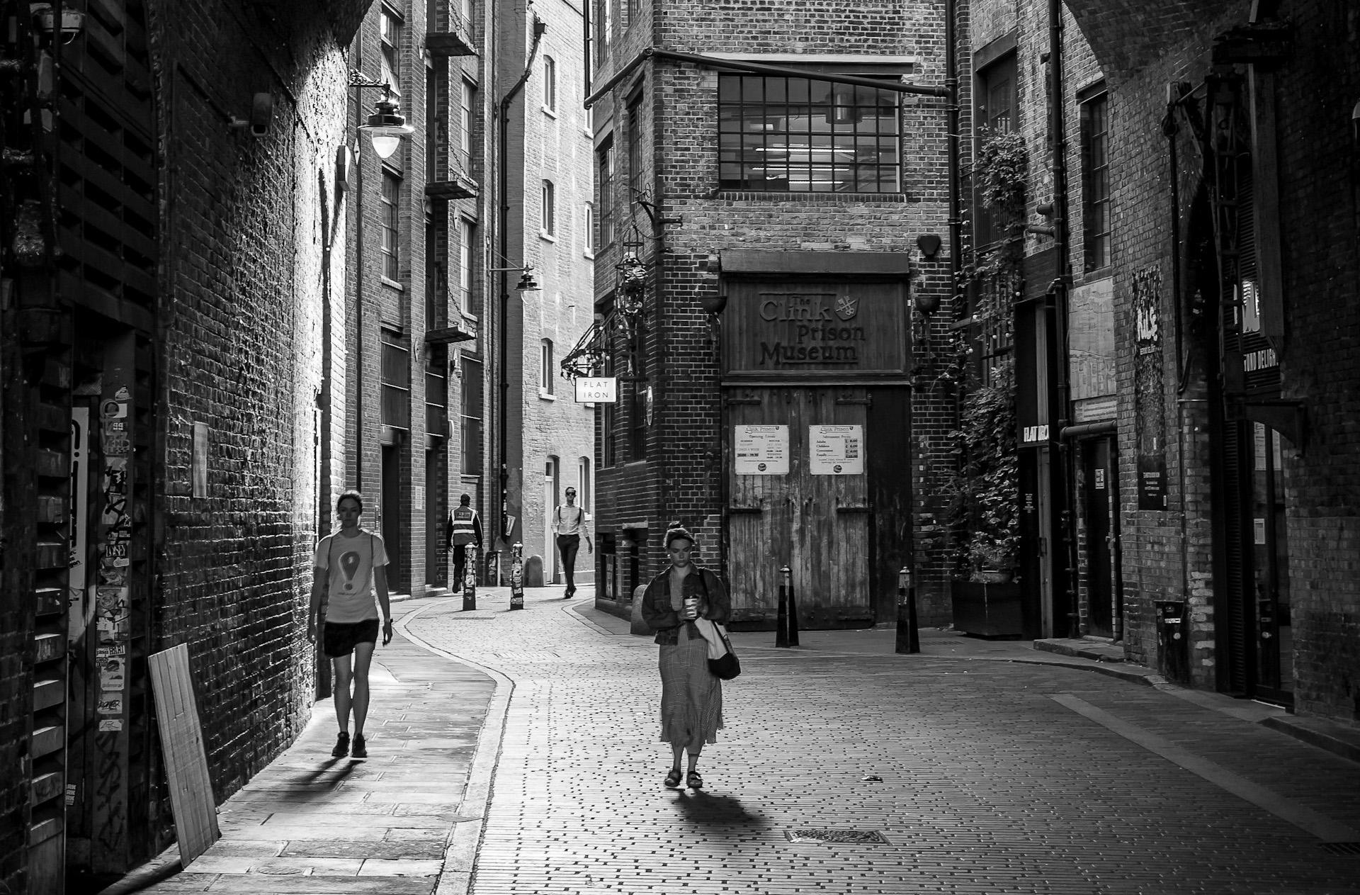 Black and white image of a woman walking under a bridge through the cobbled streets of Southwark