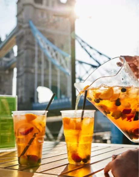 Drink being poured in glasses in front of Tower Bridge
