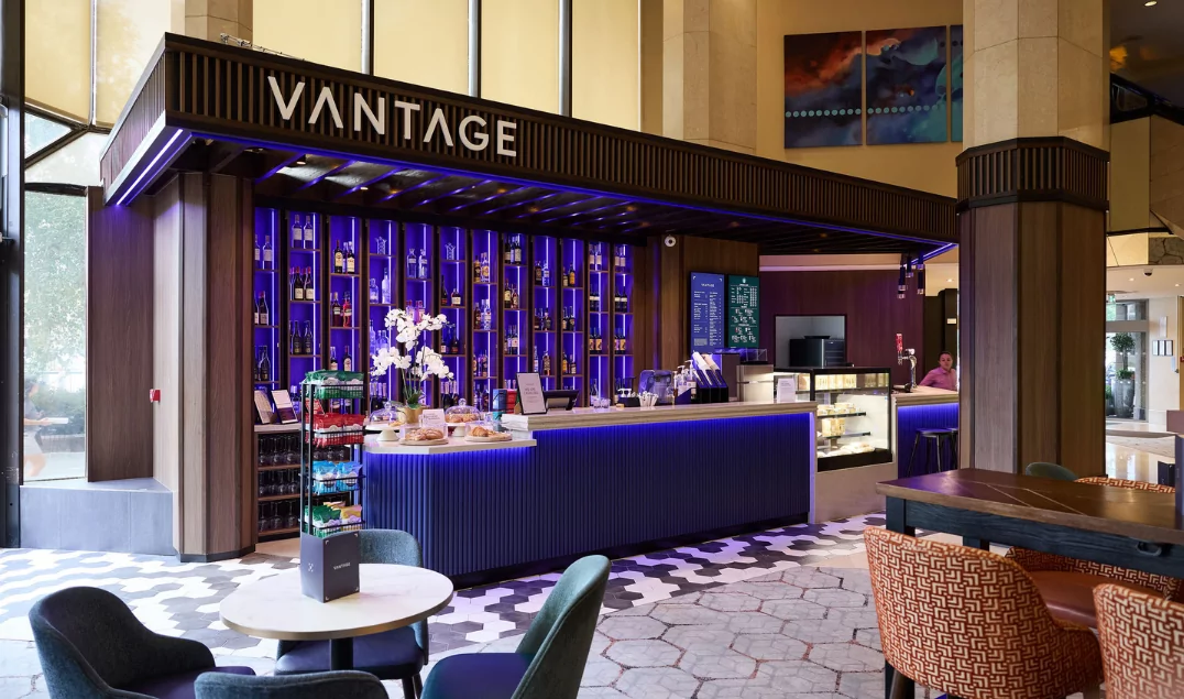 Vantage at The Tower Hotel, featuring illuminated shelving, a contemporary service counter, and lounge seating.